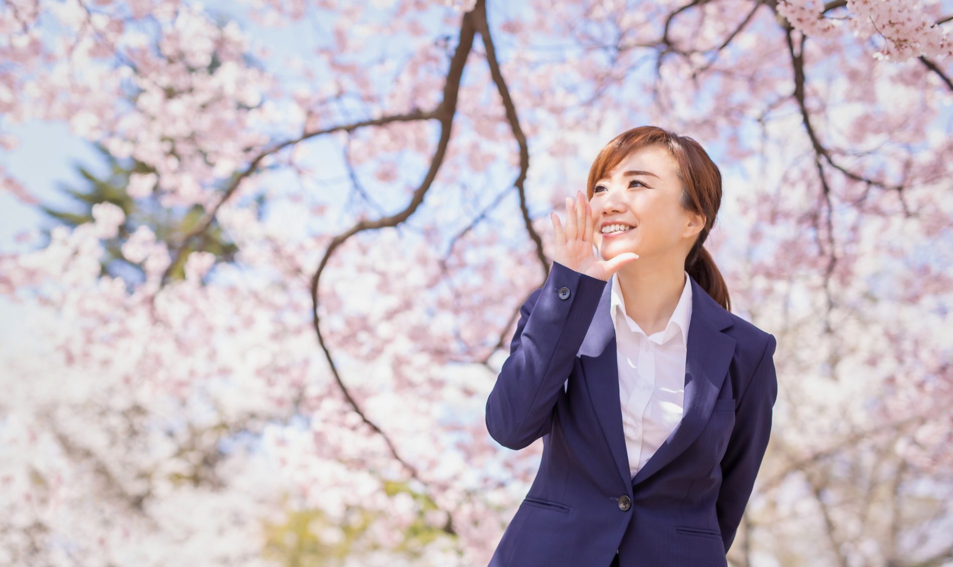 桜の下でポーズをとる女性